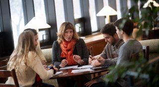 Faculty member with students sitting at table