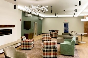 The Lee Hall Lounge, a bright space with brand-new furnishings, including modern light fixtures, a large sectional couch, and armchairs.