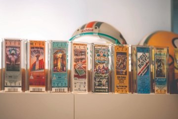 Rows of Super Bowl Tickets from years past encased in protective plastic cases.