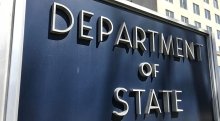 Close-up of the sign outside the State Department, which reads "Department of State" in large sans-serif silver letters in all caps.