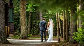 A bride and groom walk along a trail in the Adirondack mountains. 