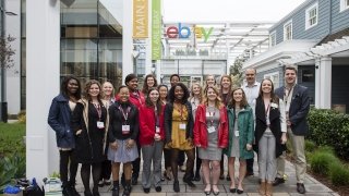 A group of 20 Saint Lawrence students stand with alumni in front of ebay.