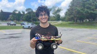 Cai Lemieux Mack '23 holds autonomous rover during his research