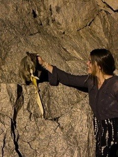 Helena pets a small animal in a cave