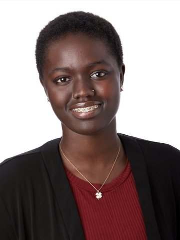 Headshot of Penda Sarr. Penda has a silver clover necklace, a nose stud, short hair and is wearing a black cardigan over a red shirt.