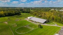 An aerial view of the Saint Lawrence University riding center. The grass and surrounding trees are vibrant green. 